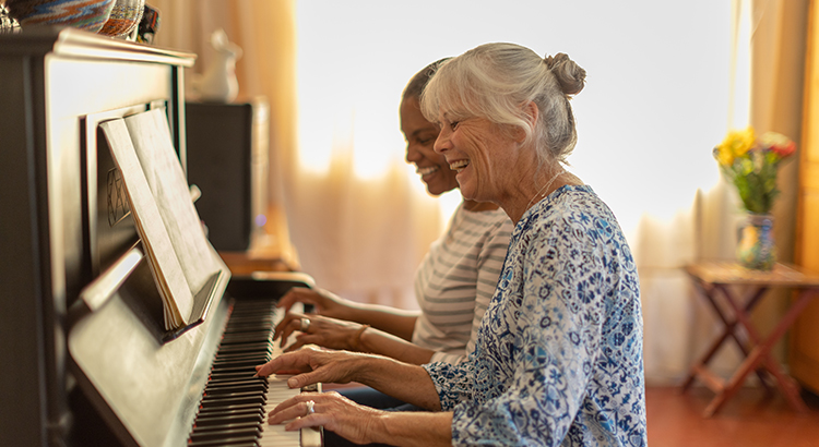 Two women playing the piano together at home