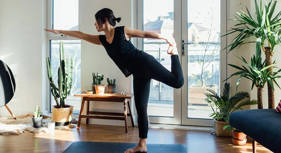 woman in black shirt and leggings doing yoga inside home