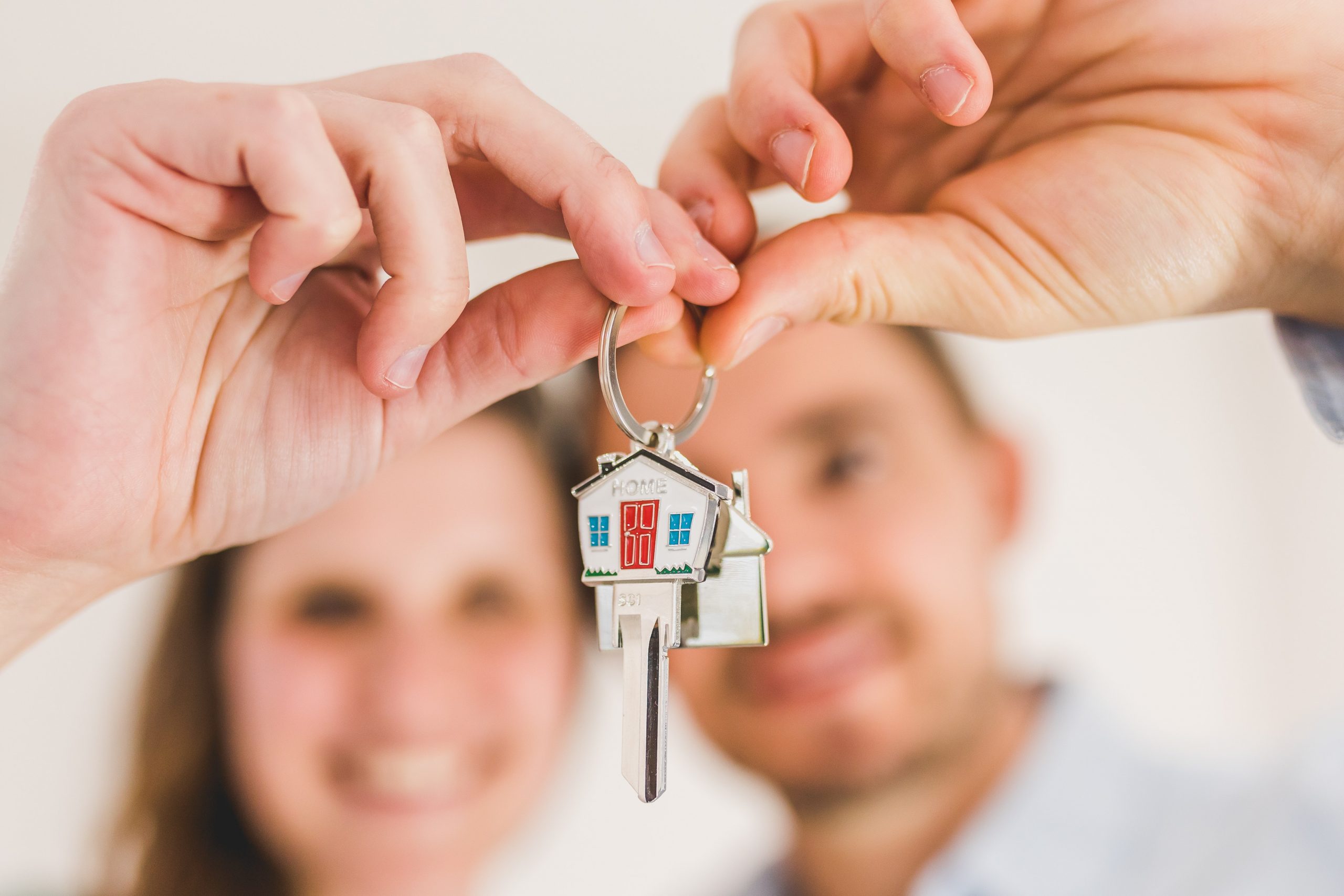 two people blurred in background holding a home key