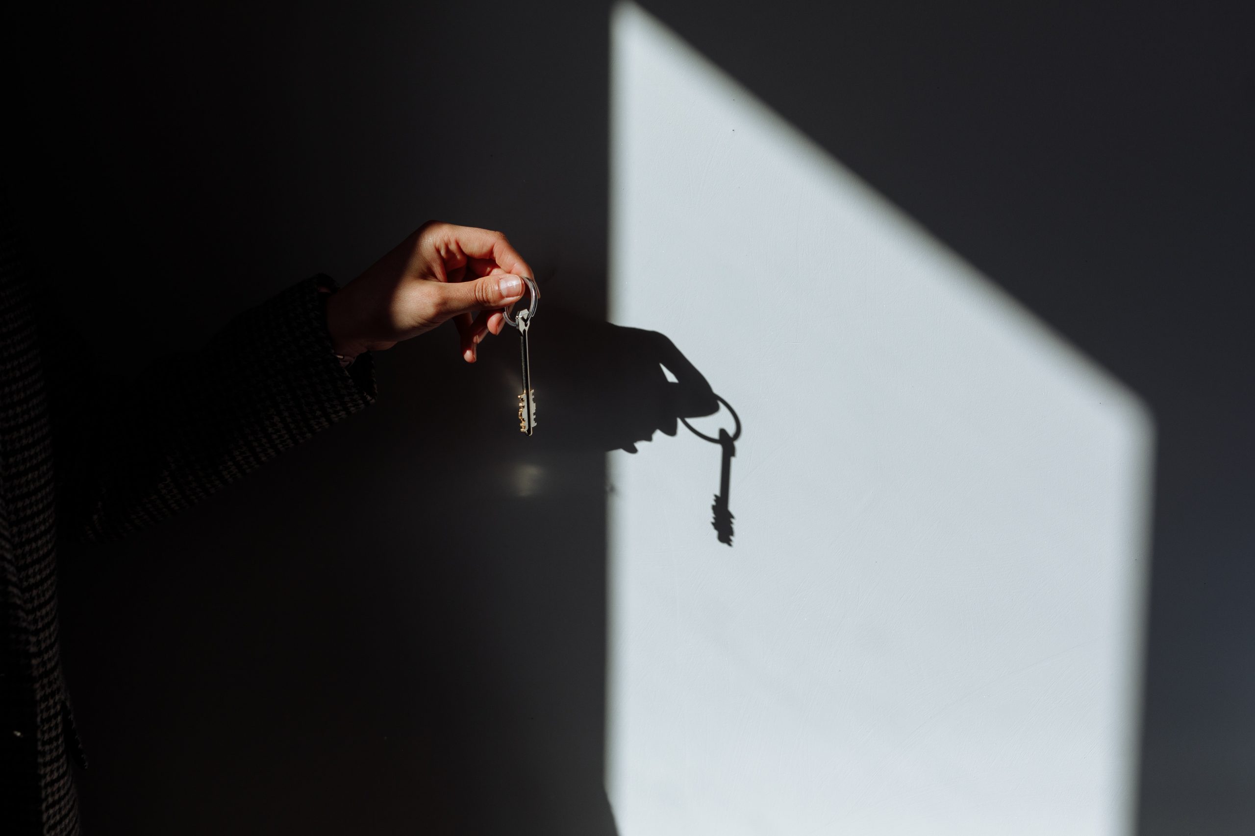 handd holding a house key behind shadows